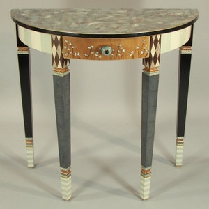 May include: A half-round table with a white and black checkered design on the front and a single drawer with a floral design. The table has three legs with black, white, and gold accents.
