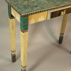 May include: A hand-painted console table with a green and blue marbled top, a single drawer, and decorative details on the legs. The drawer has a butterfly design and a gold accent.