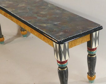May include: A hand-painted wooden bench with a black and white diamond pattern on the legs. The top of the bench is painted with a swirling pattern of brown, gray, and white. The bench has a black trim with white dots around the edge.