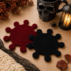 Puede incluir: Dos posavasos circulares de ganchillo, uno en rojo oscuro y otro en negro, con un diseño de rayos solares o tipo virus con múltiples protuberancias redondeadas que se extienden desde el centro, tejidos con un patrón de punto denso.