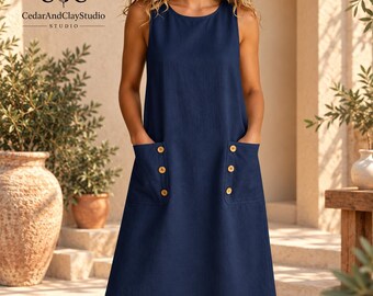 May include: A sleeveless navy blue knee-length dress featuring a round neckline and two large front patch pockets. Each pocket is adorned with three small round wooden buttons arranged vertically. The dress has a simple, straight-cut silhouette.