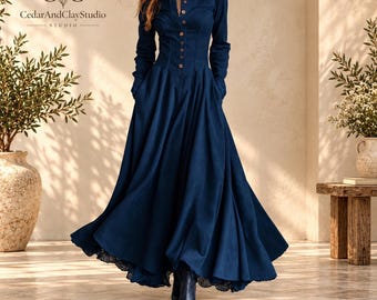 May include: A long-sleeved navy blue maxi dress featuring a button-down front with light brown buttons, a fitted bodice, and a full, flowing skirt with a dark lace trim at the hem. The dress includes a collar and long sleeves with cuffs.