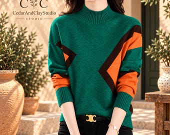 May include: A long-sleeved jumper featuring a mock neck and a colour-blocked pattern in green, orange, and dark brown. The knit garment has ribbed cuffs and a ribbed neckline. The logo for CedarAndClayStudio is visible in the upper left corner.