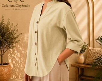 May include: A light sage green button-down shirt with a mandarin collar, long sleeves with rolled cuffs, and a curved hemline. The shirt features five visible dark brown buttons down the front placket. The logo CedarAndClayStudio is visible.