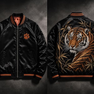 May include: A black satin bomber jacket featuring a front zip, orange and black striped ribbed collar and cuffs, and an orange paw print on the chest. The back displays a detailed embroidered tiger surrounded by bamboo stalks in orange and black.