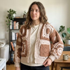 May include: A long-sleeve cardigan constructed from alternating square crochet motifs in shades of cream and brown. The garment features a ribbed collar, cuffs, and hem, with a small rectangular label attached to the lower front pocket area.