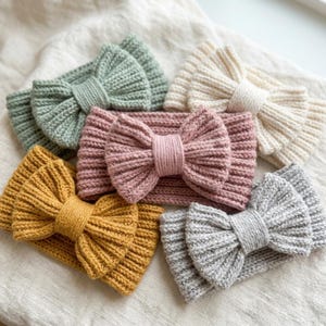 Puede incluir: Una colección de cinco diademas de punto en verde salvia, crema, rosa empolvado, amarillo mostaza y gris claro. Cada diadema presenta un lazo central prominente hecho del mismo tejido de punto acanalado que la propia banda.