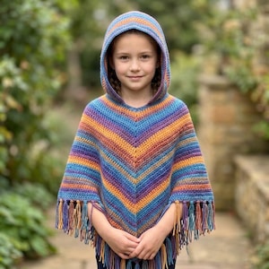May include: A hooded crochet poncho featuring a vibrant, multi-colored striped pattern in shades of blue, purple, orange, and yellow. The garment has a V-shaped front design and is finished with long, dangling fringe along the bottom hemline.