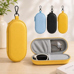 May include: A collection of oval-shaped, zippered hard-shell cases with black carabiner clips. The cases come in yellow, light blue, and black. One yellow case is open, revealing a gray interior lining holding a pair of eyeglasses and sunglasses.