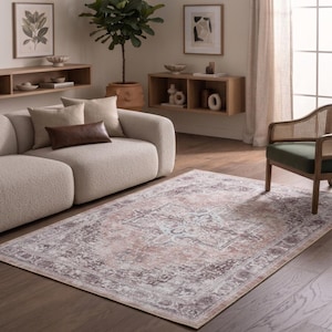 May include: A rectangular area rug featuring a faded, distressed pattern in shades of dusty rose, soft gray, and cream. The design includes a central medallion surrounded by intricate floral and geometric borders, creating a vintage-inspired look.