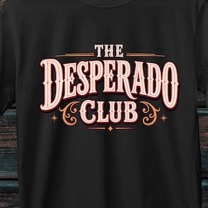 Peut inclure: Un t-shirt noir à manches courtes avec le texte THE DESPERADO CLUB imprimé dans une police de couleur claire stylisée avec des fioritures décoratives. Le motif est centré sur la poitrine du t-shirt, qui possède un col rond et une coupe standard.