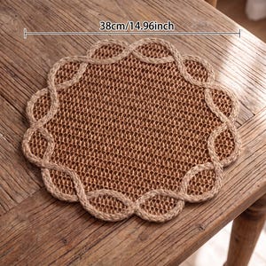 May include: A round, woven brown placemat with a scalloped, braided border. The placemat features a textured, natural fiber construction and measures 14.96 inches in diameter as indicated by the text overlay on the image.
