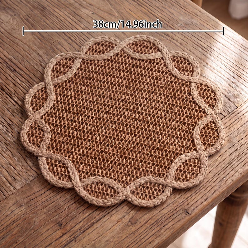 May include: A round, woven brown placemat with a scalloped, braided border. The placemat features a textured, natural fiber construction and measures 14.96 inches in diameter as indicated by the text overlay on the image.