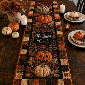 May include: A rectangular quilted table runner featuring a black center panel with embroidered autumn leaves, pumpkins, and a jack-o'-lantern. The text "The Smith Family" is embroidered in the center. The border consists of a patchwork of squares.