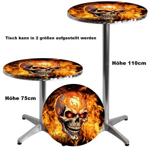 Op de afbeelding: Een ronde metalen tafel met een afbeelding van een brandende schedel op het blad. De tafel wordt getoond in twee hoogtes, 75 cm en 110 cm, met een zilverkleurige centrale poot en een vierpotige voet. De tekst luidt: Tisch kann in 2 größen aufgestellt werden.