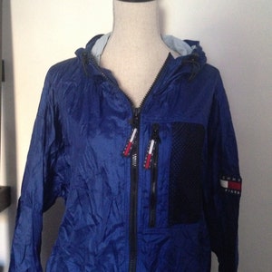 May include: A blue hooded jacket with a black zipper and a Tommy Hilfiger logo on the sleeve.