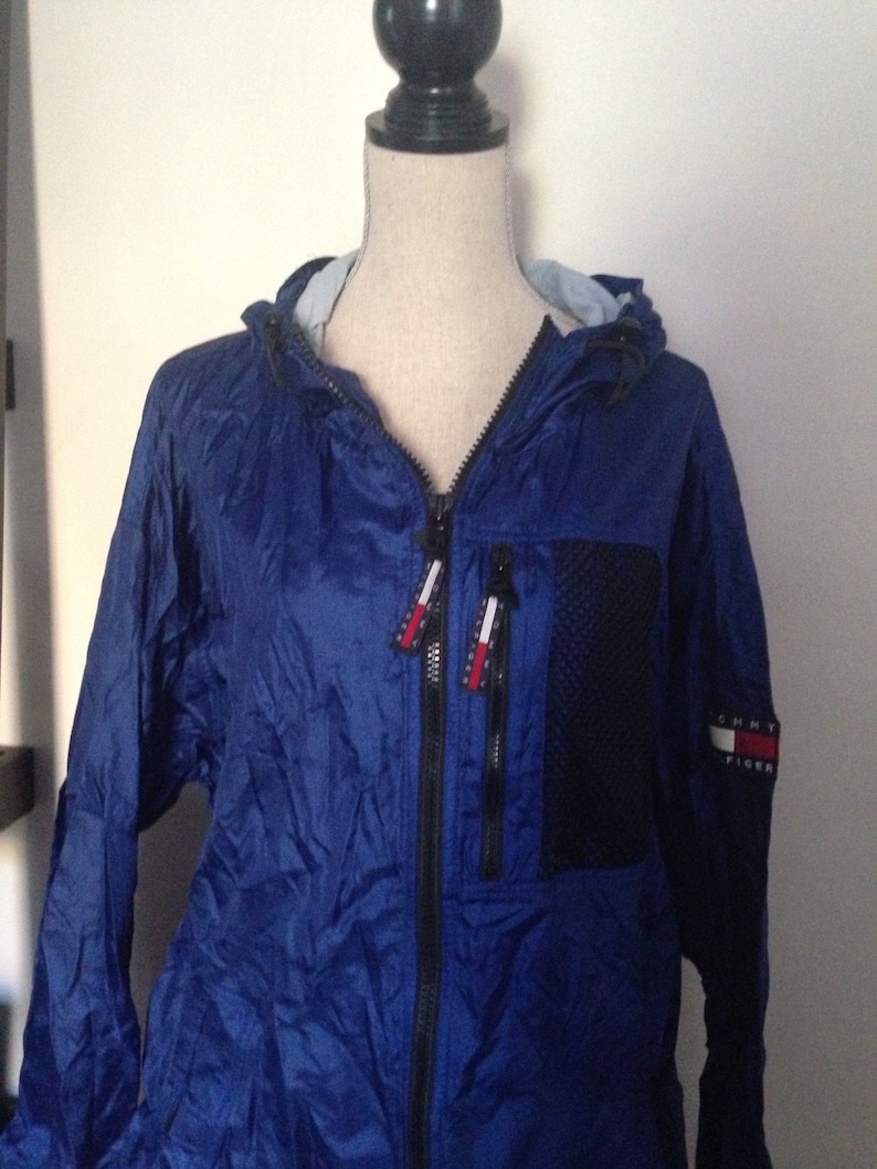 May include: A blue hooded jacket with a black zipper and a Tommy Hilfiger logo on the sleeve.
