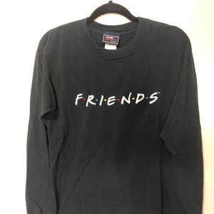 May include: Black long-sleeve t-shirt with the word "FRIENDS" in white with colorful dots, a logo for the NBC television show.