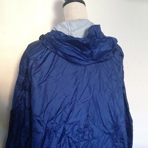 May include: A blue hooded jacket with a zipper closure. The jacket is made of a lightweight, water-resistant material.