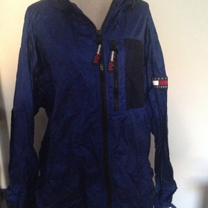 May include: A blue hooded jacket with a black zipper and a Tommy Hilfiger logo on the left sleeve.