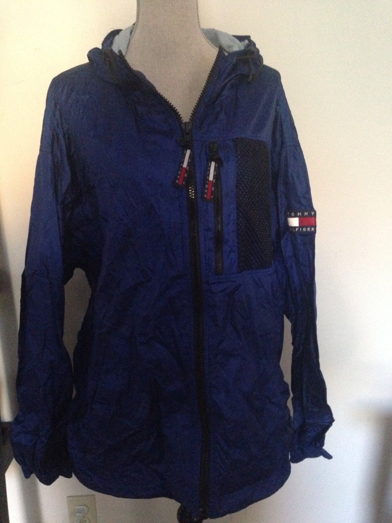 May include: A blue hooded jacket with a black zipper and a Tommy Hilfiger logo on the left sleeve.