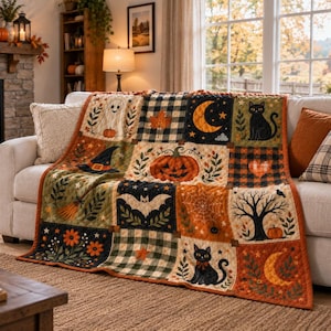 May include: A rectangular patchwork quilt featuring a Halloween theme with squares displaying a ghost, a jack-o'-lantern, black cats, a witch hat, a bat, a spider web, a bare tree, moons, stars, and orange flowers, all set against a plaid background.