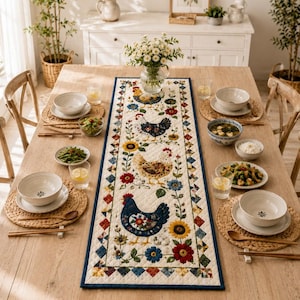 May include: A rectangular quilted table runner featuring a cream-colored background with a central pattern of four chickens in various colors, surrounded by sunflowers and red and blue flowers, all bordered by a small colorful diamond-shaped trim.