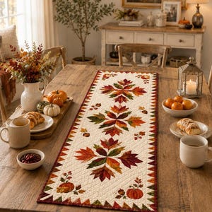 May include: A rectangular fabric table runner featuring a cream-colored background with a quilted texture. The design displays repeating patterns of autumn leaves in shades of orange, red, and brown, accented with small pumpkins and acorns.