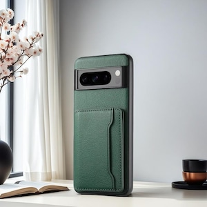 Op de afbeelding: Een donkergroen smartphonehoesje met een textuur die aan leer doet denken en een geïntegreerd vakje voor pasjes aan de achterkant. Het hoesje heeft een zwarte cameramodule met drie lenzen en een flitser voor een rechthoekig mobiel apparaat.