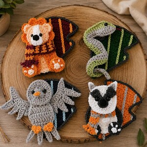 May include: Four handmade crochet animal figures including a lion with a maroon and gold scarf, a green snake, a gray owl with orange feet, and a white and black raccoon with an orange and gray scarf, each attached to a colorful fabric wing shape.