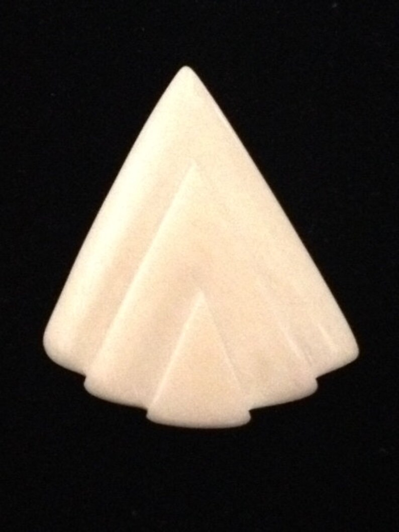 Op de afbeelding: Een witte, gegraveerde, driehoekige hanger met een geometrisch ontwerp.