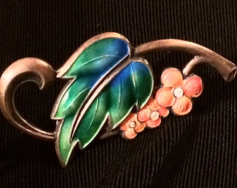 May include: A silver brooch with a green and blue enamel leaf and a cluster of pink enamel flowers.