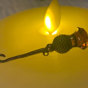 May include: A silver bottle stopper with a decorative thistle design and a clear amber glass top.