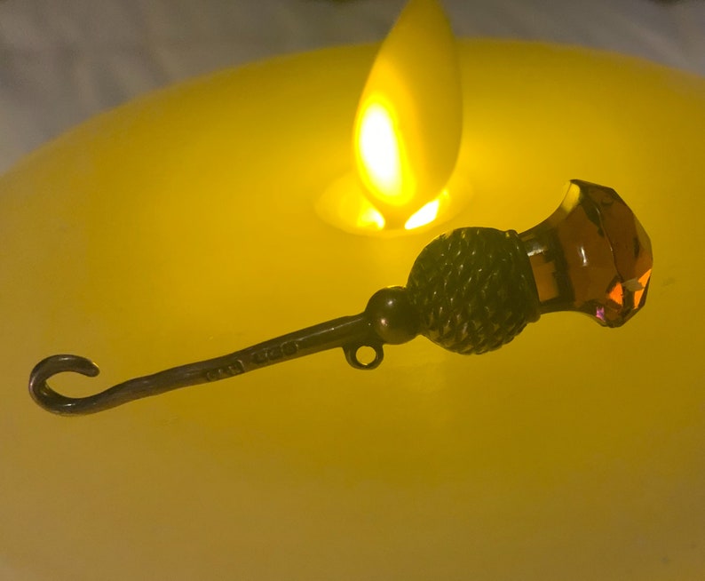 May include: A silver bottle stopper with a decorative thistle design and a clear amber glass top.