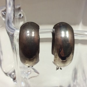 May include: A pair of silver hoop earrings. The earrings are smooth and have a shiny finish.