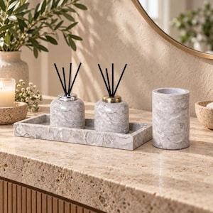 Peut inclure: Un ensemble composé de deux diffuseurs de parfum à bâtonnets noirs avec un motif marbré gris, un plateau rectangulaire assorti et un porte-accessoires cylindrique. Les diffuseurs présentent des bouchons métalliques argentés et dorés.