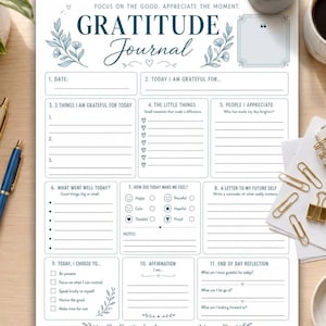 May include: A white gratitude journal page with dark blue text and floral accents. The layout includes sections for date, gratitude lists, daily reflections, feelings, affirmations, and a letter to self. The text reads Gratitude Journal.