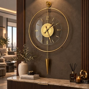 Puede incluir: Un reloj de pared circular con marco de metal dorado y esfera transparente. El centro tiene una placa circular dorada con patrón de greca, manecillas doradas e índices dorados. Una varilla vertical dorada sostiene un péndulo cónico.
