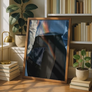 May include: A framed rectangular print featuring a person wearing a light blue button-down shirt tucked into black trousers. A subtle rainbow light refraction effect is cast across the centre of the image, overlaying the clothing and fabric.