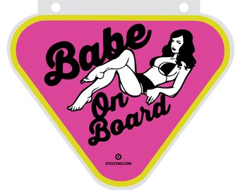 Może przedstawiać: Różowy naklejka w kształcie trójkąta z czarno-białym obrazkiem kobiety w bikini z tekstem "Babe On Board" w kolorze czarnym.