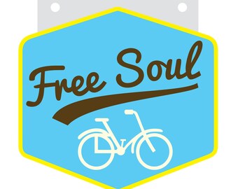 Może przedstawiać: Sechokątny znak w kolorze niebieskim i żółtym z napisem "Free Soul" w brązowych literach ozdobnych. Pod napisem znajduje się biała sylwetka roweru.