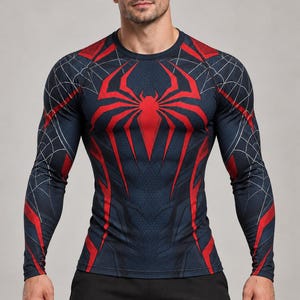 May include: A long-sleeve compression shirt featuring a dark navy blue base with a large red spider emblem on the chest and red accents on the shoulders and sides. The fabric displays a subtle black spiderweb pattern across the sleeves.