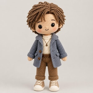 May include: A handcrafted crochet doll featuring brown yarn hair, a cream-colored turtleneck sweater, a blue coat with two buttons, brown trousers with a belt, and cream-colored sneakers. The doll has black eyes and a small necklace with a circular pendant.