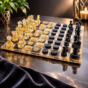 Op de afbeelding: Een vierkant spelbord met een raster van zwarte en goud gespikkelde harsvierkanten. De ene kant bevat doorzichtige schaakstukken met goudvlokken, terwijl de andere kant effen zwarte schaakstukken bevat. Het bord bevat ook doorzichtige damstenen.