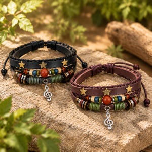 Op de afbeelding: Twee meerlaagse armbanden, één zwart en één bruin, voorzien van goudkleurige sterren, diverse houten en metalen kralen in rood, blauw, groen en beige, en een zilverkleurige muzieksleutelbedel in het midden van elke band.