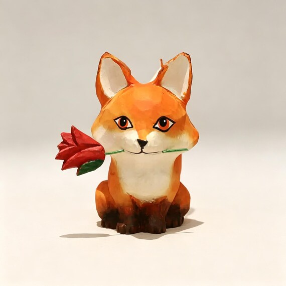 A hand-carved wooden fox clutching a tiny rose — the kind of desk sculpture that makes visitors stop and ask 'where did you get that?'