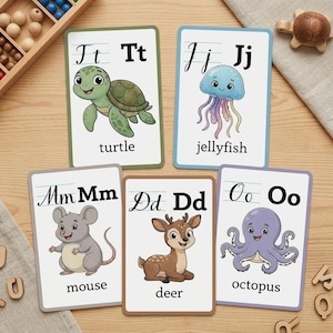 Puede incluir: Cinco tarjetas educativas rectangulares con letras e ilustraciones de animales. Las tarjetas muestran T para tortuga, J para medusa, M para ratón, D para ciervo y O para pulpo. Cada tarjeta incluye letras mayúsculas y minúsculas.