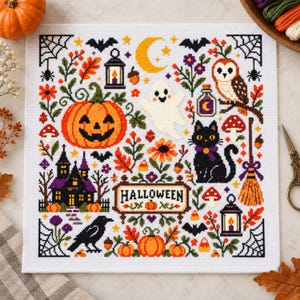 Può includere: Un ricamo a punto croce quadrato su tessuto bianco con un cartello centrale di Halloween circondato da una zucca, un fantasma, un gatto nero, un gufo, una casa stregata, un corvo, una scopa, lanterne, ragnatele e fogliame autunnale.