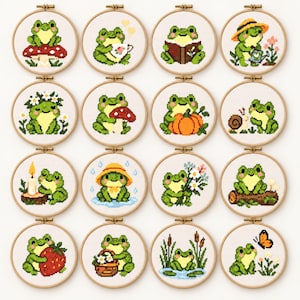 May include: A collection of sixteen circular wooden embroidery hoops, each containing a cross-stitch pattern of a green frog in various activities, including sitting on a mushroom, reading a book, gardening, holding a strawberry, and interacting with nature.