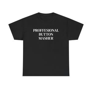 May include: A black short-sleeved t-shirt featuring the white text PROFFESIONAL BUTTON MASHER centered on the chest. The garment has a crew neckline and a standard fit, displaying the text in a clean, bold, sans-serif font style.
